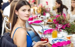 A young charming girl in a blue dress is sitting at a...
