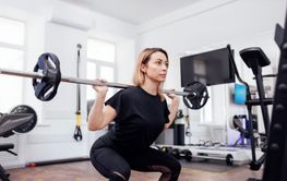 Strained pretty sportswoman in black sportswear lifting...