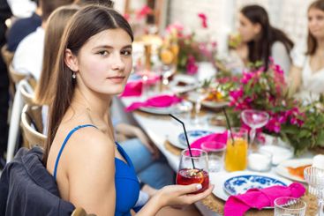 A young charming girl in a blue dress is sitting at a...