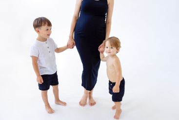 Pregnant woman holds hands with two cute children. Young...