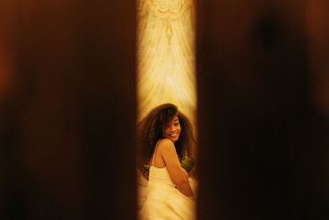 Cute African sitting on the bed and smiling in a hotel...