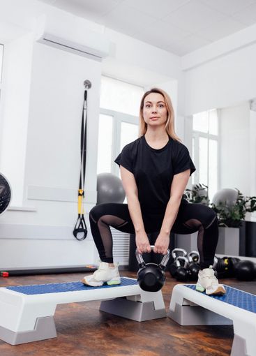Young woman in black sportswear standing on steps and...