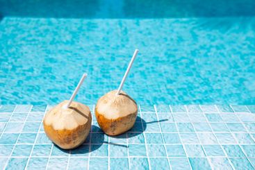 Close-up of two coconuts with straws on the side of the...