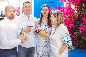 Two married couples drink cocktails and chat at a...
