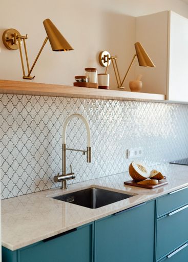 A modern kitchen with a blue set and a marble countertop