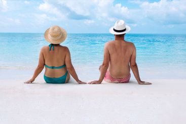 Young married couple is sitting on sand on beach and...
