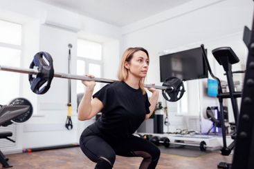 Strained pretty sportswoman in black sportswear lifting...