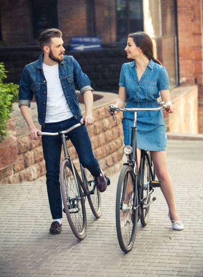 Young couple sitting on a bicycle opposite city 