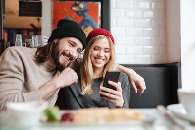 Laughing Couple looking at phone in cafe