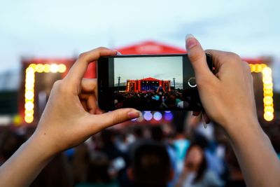 A girl is taking pictures of a street concert on the phone