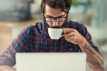 Man, laptop and coffee in office for agency with online...