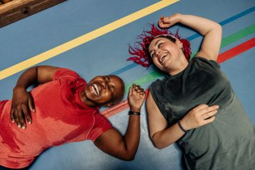 High angle view of female athletes laughing while lying...