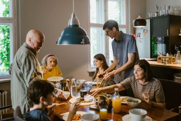 Multi-generation family having dinner at dining table in...